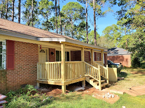 Freshly built raised wooden front porch with railings and steps on a red brick home